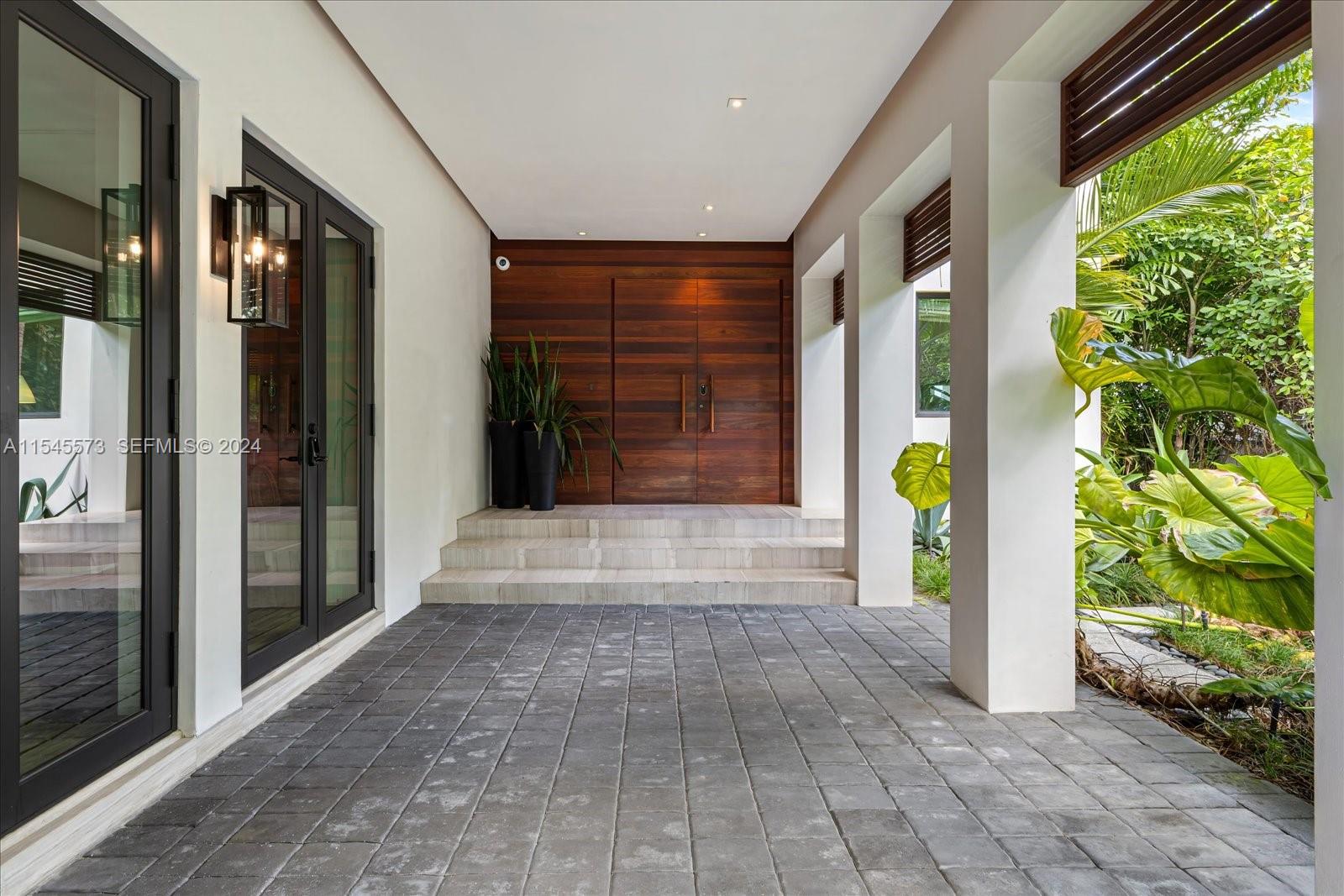 A covered entryway features a wooden double door, stone steps, and dark paver flooring — 401 E Rivo Alto Dr, Miami Beach FL 33139, MIAMI BEACH, FL