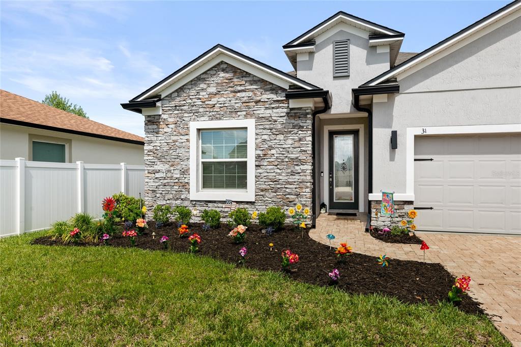 A single-story house exterior features a stone facade, a front door, and a paved driveway — 31 OLIVINE COURT, ST AUGUSTINE, FL