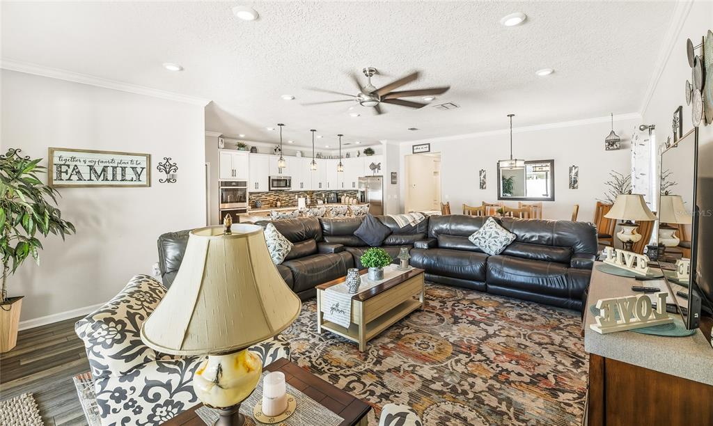 A living room with a large sectional sofa, patterned rug, and an open kitchen area — 31 OLIVINE COURT, ST AUGUSTINE, FL
