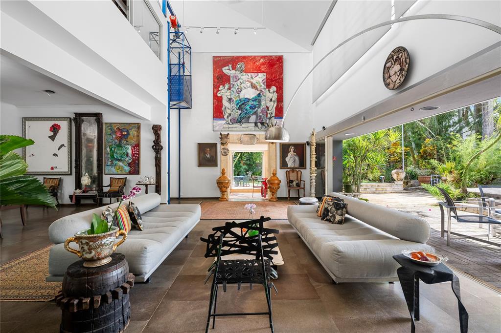 A spacious living room features high ceilings, large art pieces, two sofas, and open-air access — 3 PEDROSA STREET GARDEN HILLS, GUAYNABO, PR