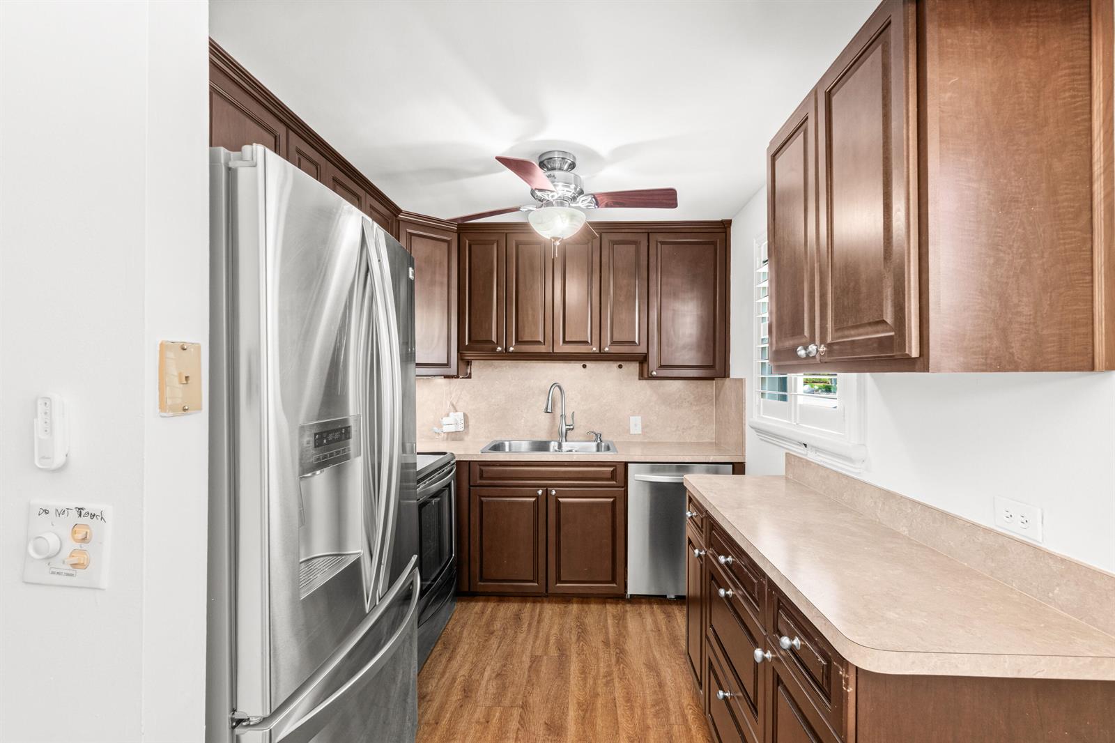 A kitchen features dark wood cabinets, stainless steel appliances, and light-colored countertops — 434 Mansfield K, Boca Raton FL 33434, BOCA RATON, FL