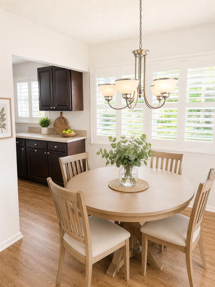 A dining area features a round wooden table, four chairs, and a chandelier near shutters — 434 Mansfield K, Boca Raton FL 33434, BOCA RATON, FL