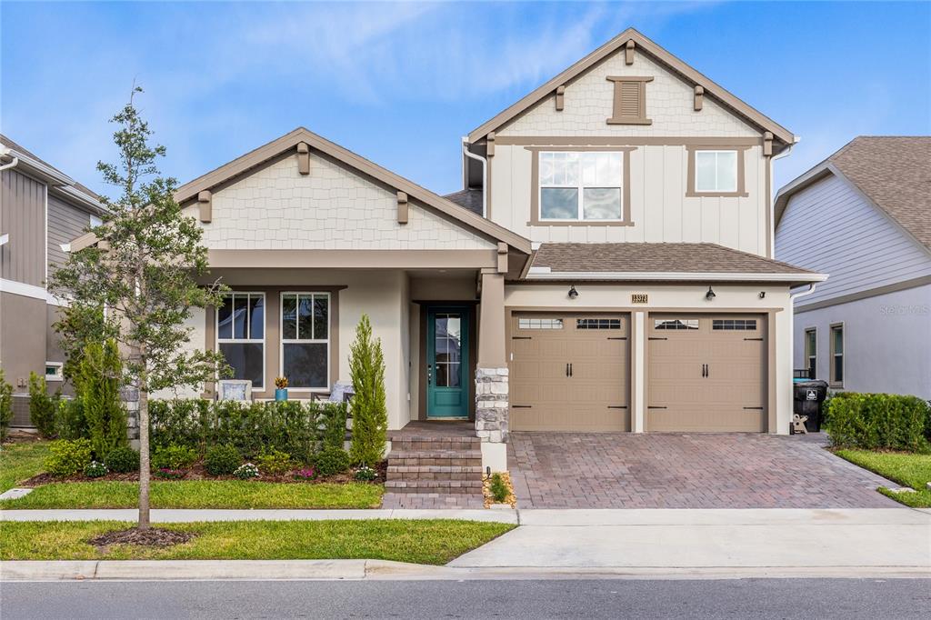 A two-story suburban house features a tan exterior, a two-car garage, and a front porch — 13373 MCMILLAN DRIVE, ORLANDO, FL