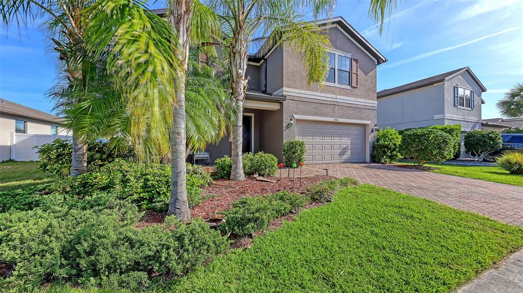 A two-story house features a paved driveway, palm trees, and a landscaped front yard — 2446 CARNATION COURT, NORTH PORT, FL
