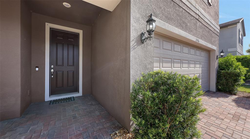 A dark front door and a beige garage door are set against a stucco exterior — 2446 CARNATION COURT, NORTH PORT, FL