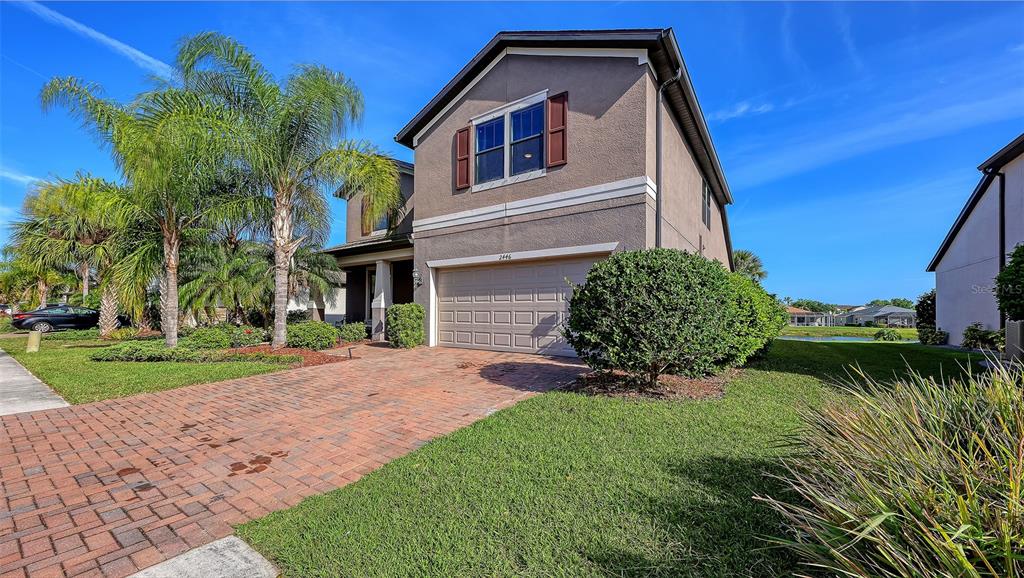 A two-story house with a brick driveway, a two-car garage, and palm trees — 2446 CARNATION COURT, NORTH PORT, FL
