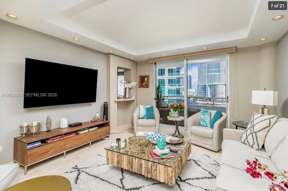 A living room features a large television, a wooden coffee table, and a balcony view — 888 Brickell Key Dr # 1004, Miami FL 33131, MIAMI, FL