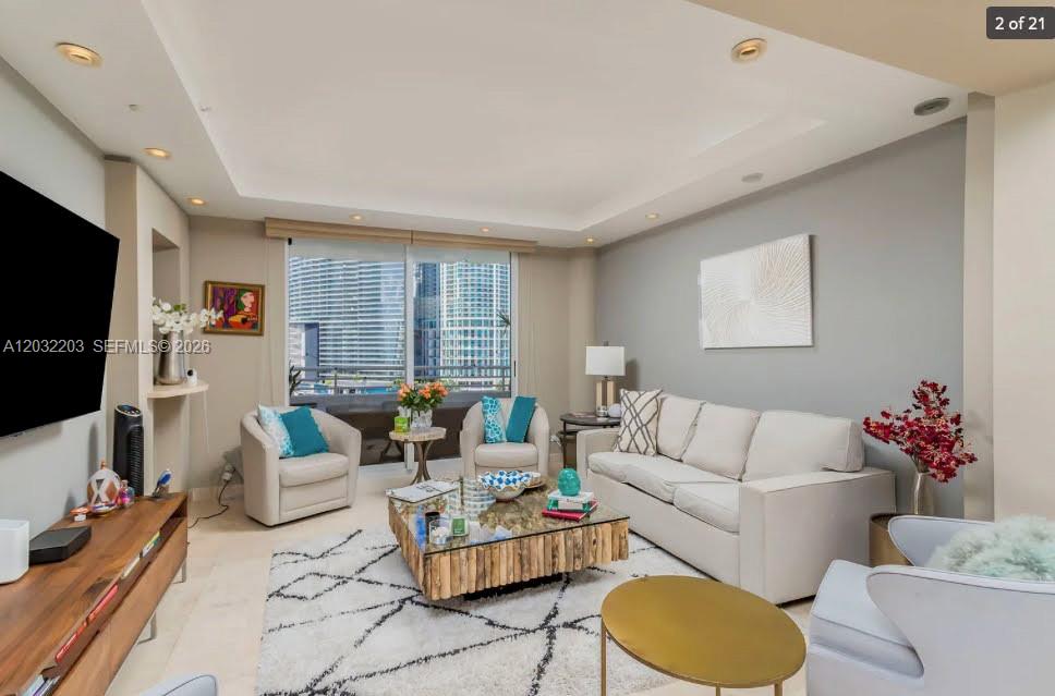 A living room features a white sofa, a wooden coffee table, and a city view — 888 Brickell Key Dr # 1004, Miami FL 33131, MIAMI, FL