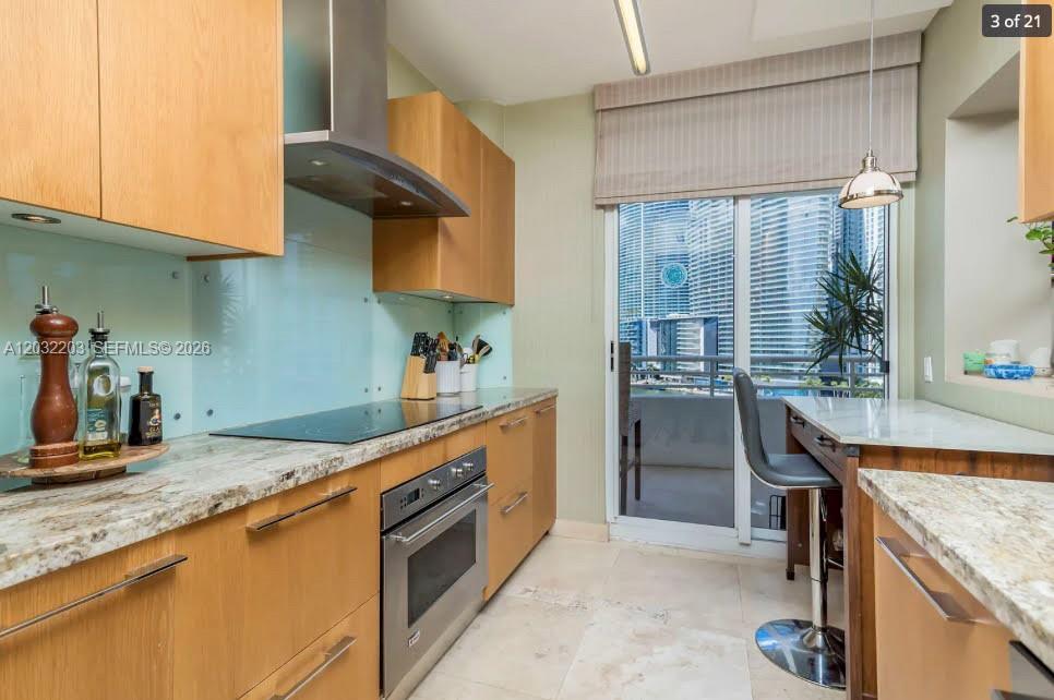 A kitchen features light wood cabinets, stone countertops, stainless steel appliances, and a balcony view — 888 Brickell Key Dr # 1004, Miami FL 33131, MIAMI, FL