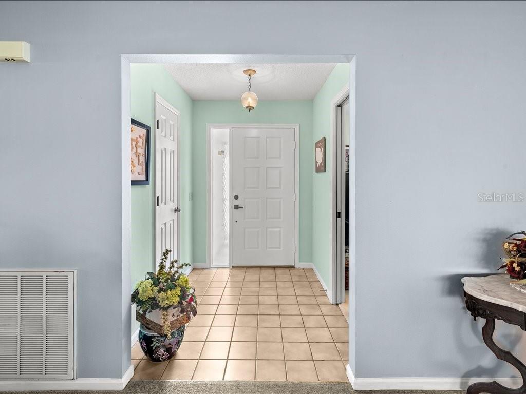 A tiled entryway features a white front door, light green walls, and a hanging light — 322 FALLING WATERS LANE UNIT 163, ENGLEWOOD, FL