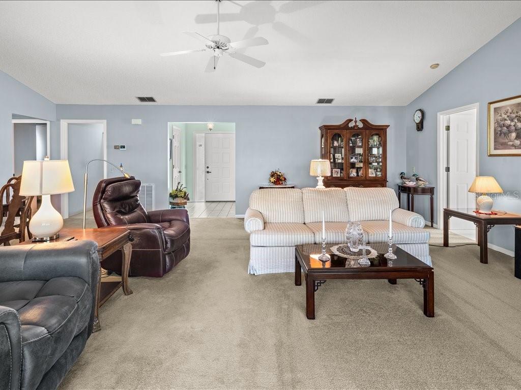 A living room features a striped sofa, a dark leather recliner, and a coffee table — 322 FALLING WATERS LANE UNIT 163, ENGLEWOOD, FL