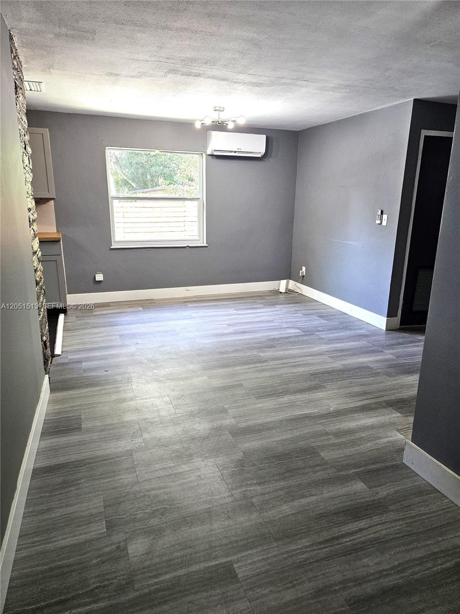 A gray-walled room features wood-look flooring, a window, and a wall-mounted air conditioning unit — 5627 SW 26th St # 0, West Park FL 33023, WEST PARK, FL