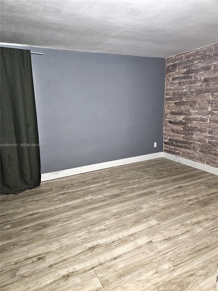 A room features gray walls, a faux brick accent wall, and light wood-look flooring — 5627 SW 26th St # 0, West Park FL 33023, WEST PARK, FL