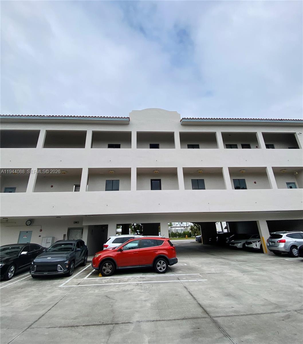 This exterior view shows a multi-story apartment building with covered parking on the ground level — PALMETTO BAY, FL
