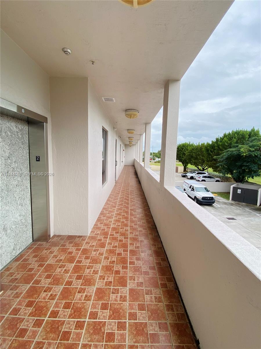 An outdoor second-floor walkway features tiled flooring, a metal elevator door, and a concrete railing — PALMETTO BAY, FL