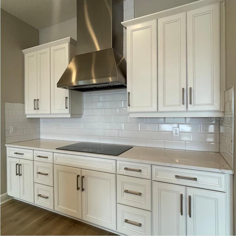 A kitchen features white cabinets, a stainless steel range hood, and a white subway tile backsplash — 4364 CURACAO PLACE, KISSIMMEE, FL