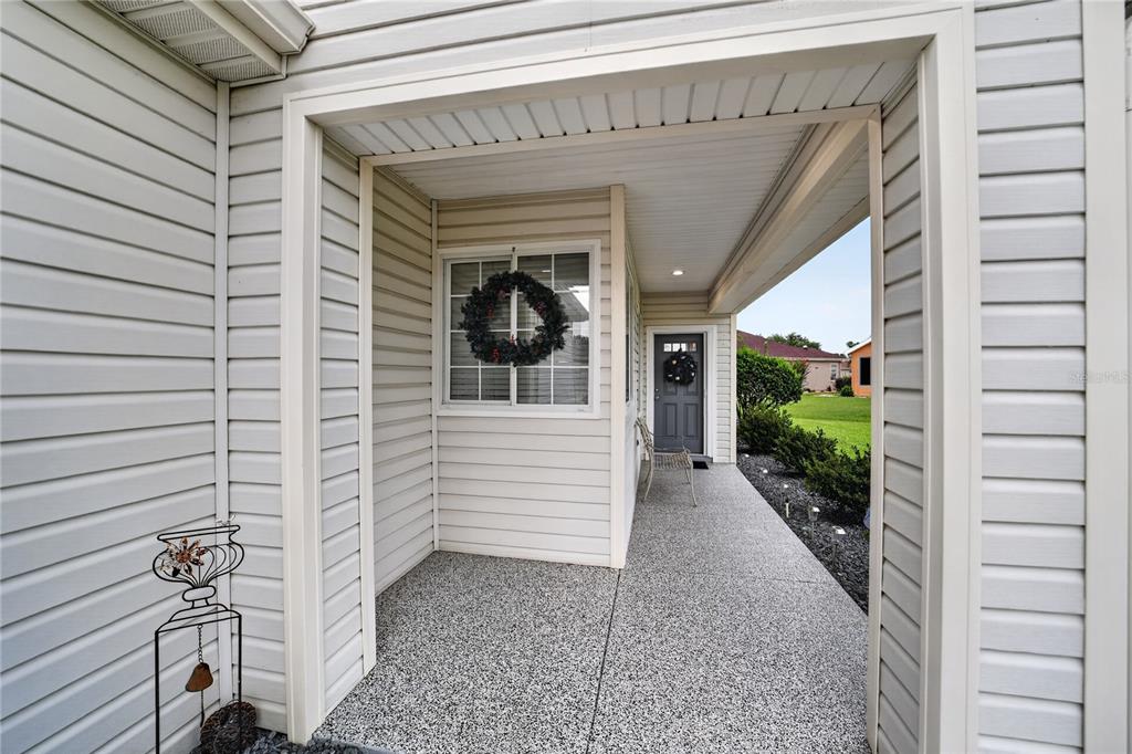 A covered front porch features light-colored siding, a concrete floor, and a dark entry door — 12771 SE 92ND TERRACE, SUMMERFIELD, FL