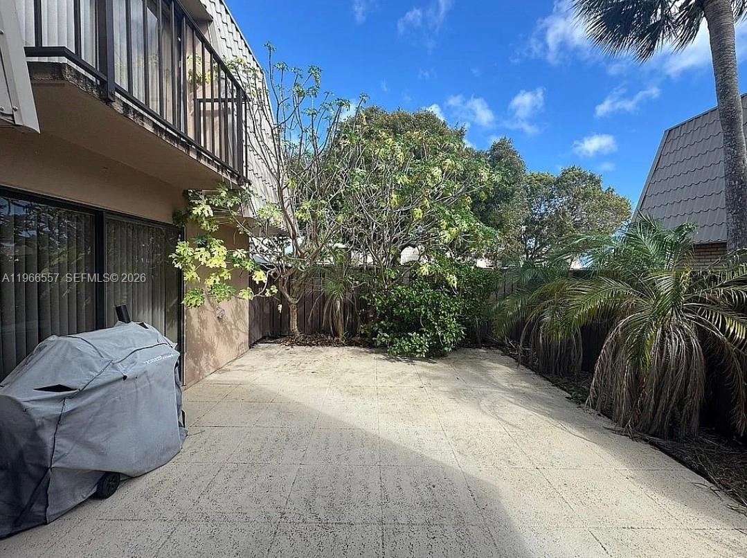 A paved patio area features a covered grill, trees, and a wooden privacy fence — 6222 62nd Way, West Palm Beach FL 33409, WEST PALM BEACH, FL