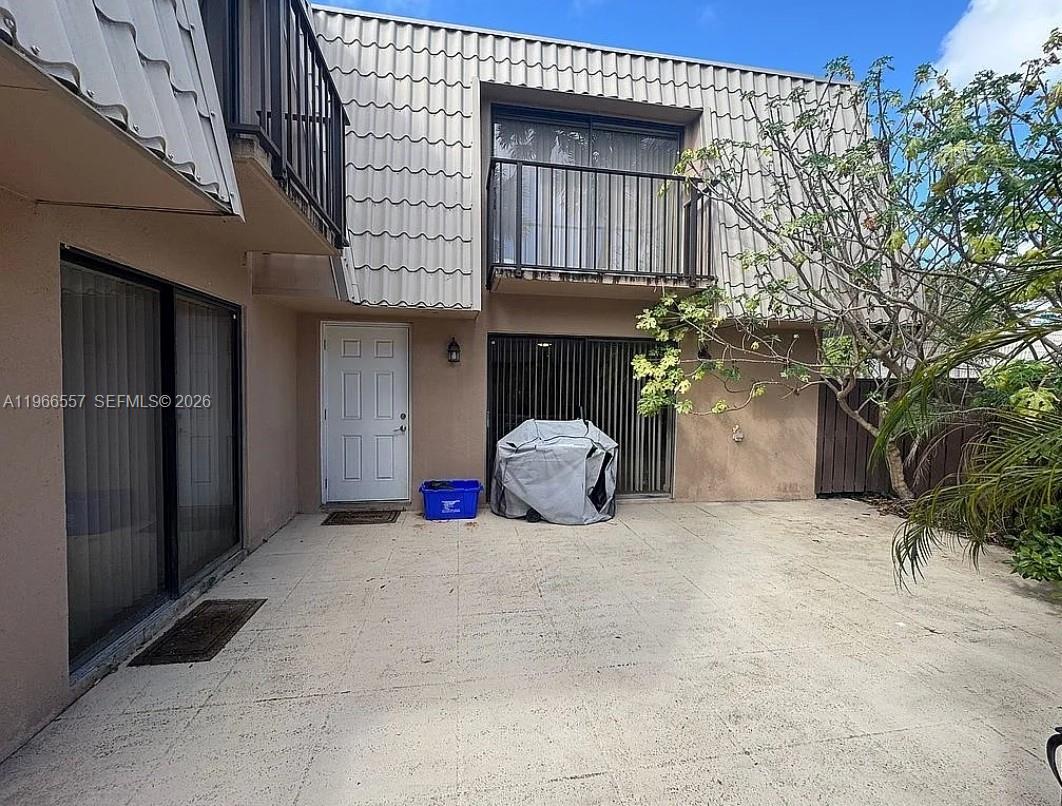 A two-story townhouse exterior features a concrete patio, a white front door, and balconies — 6222 62nd Way, West Palm Beach FL 33409, WEST PALM BEACH, FL
