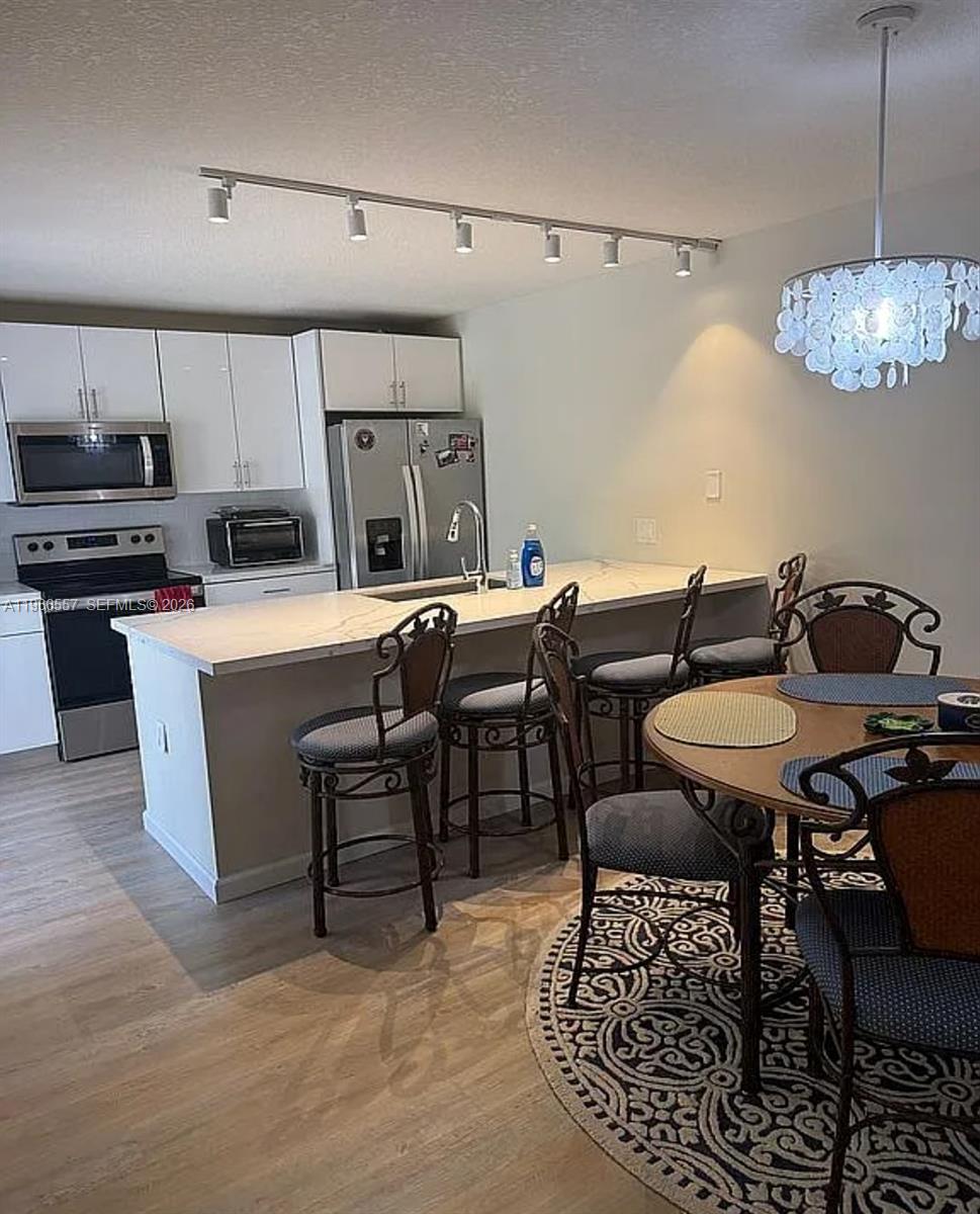 A kitchen with white cabinets, stainless steel appliances, a breakfast bar, and a dining area — 6222 62nd Way, West Palm Beach FL 33409, WEST PALM BEACH, FL