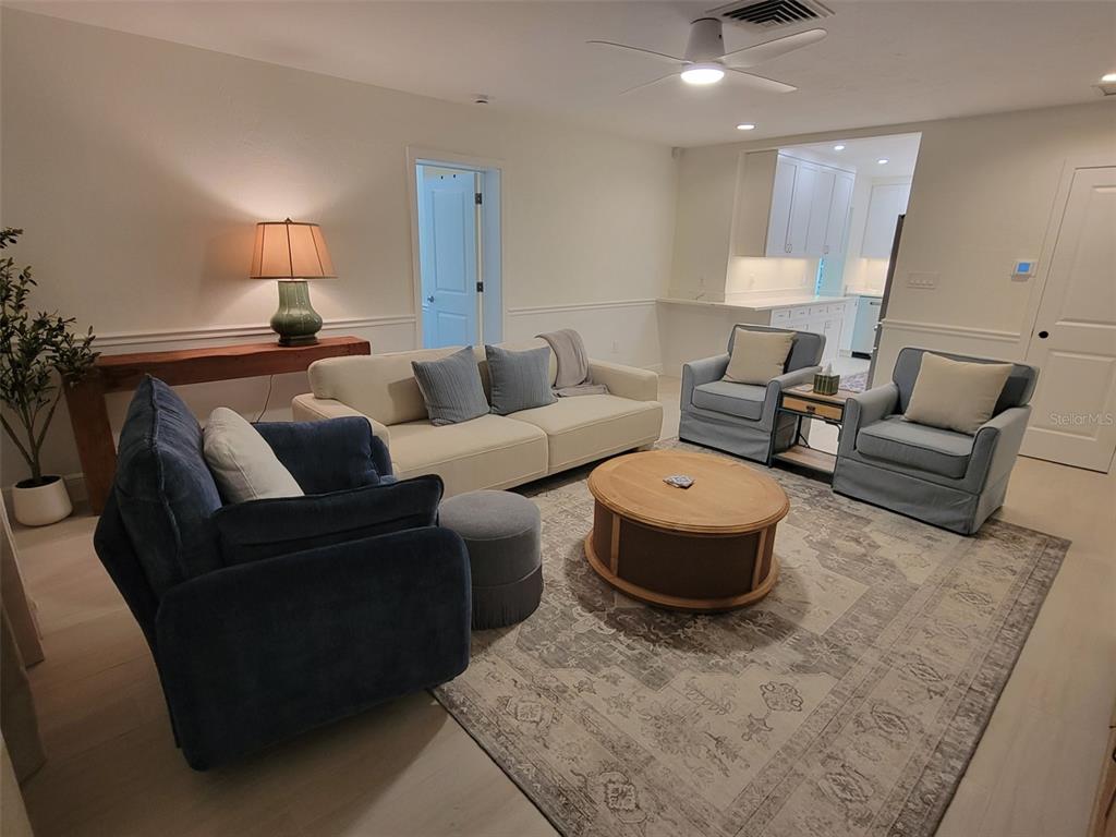 A living room features a sofa, armchairs, a round coffee table, and a patterned area rug — 323 MADISON DRIVE, SARASOTA, FL