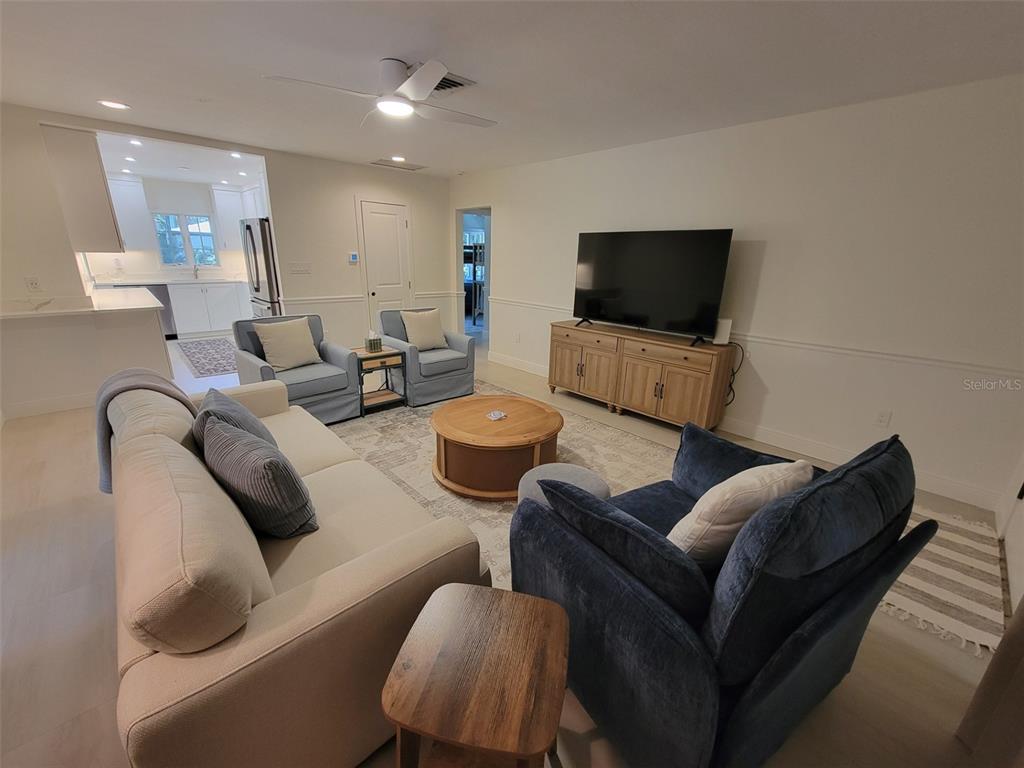 A living room features a sofa, armchairs, a television on a wooden console, and light flooring — 323 MADISON DRIVE, SARASOTA, FL