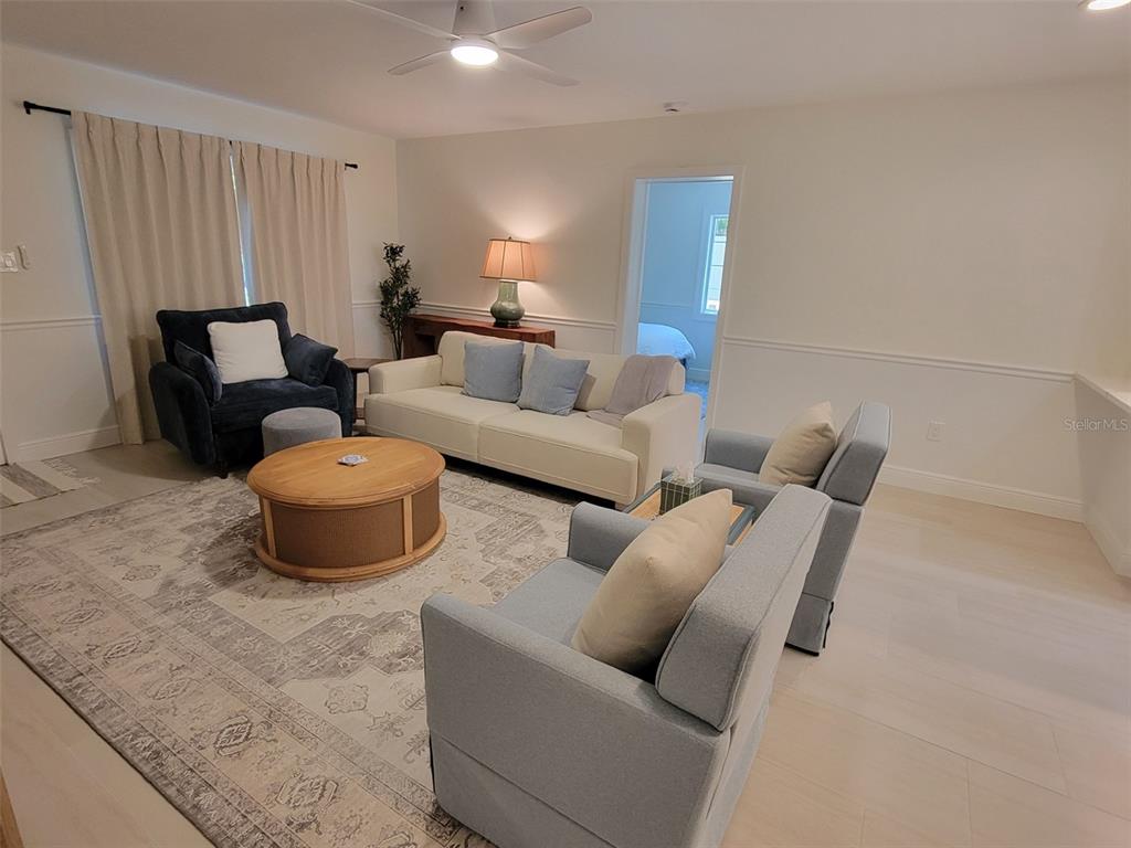 A living room features a beige sofa, blue armchairs, a round coffee table, and area rug — 323 MADISON DRIVE, SARASOTA, FL