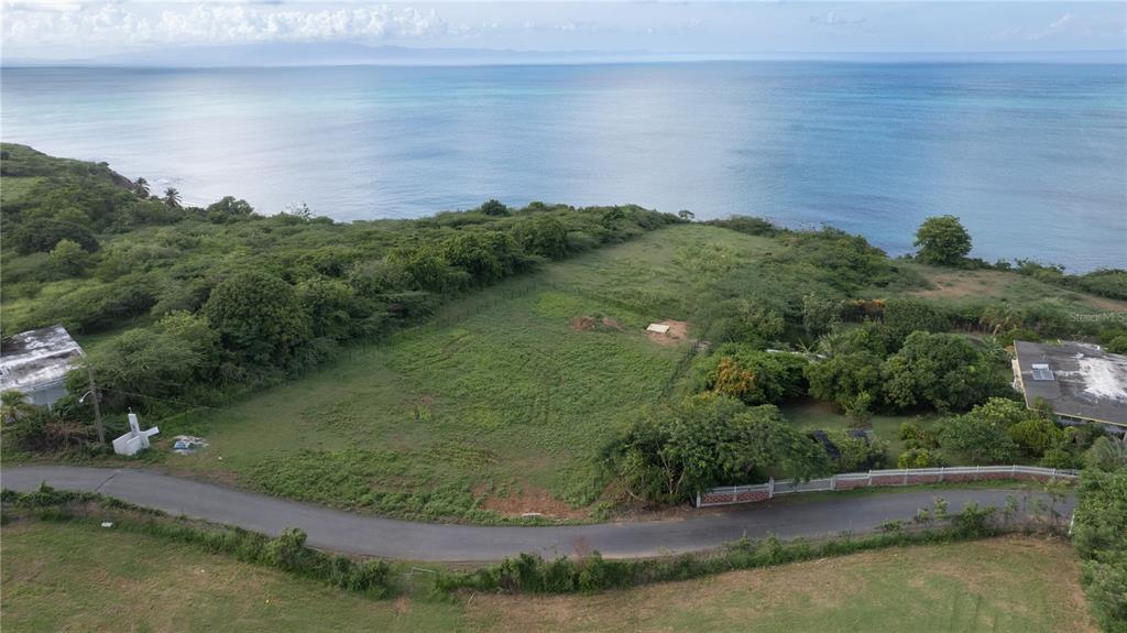 An aerial view shows a grassy coastal lot bordered by a road and the ocean — 2 CALLE CAÑON, VIEQUES, PR