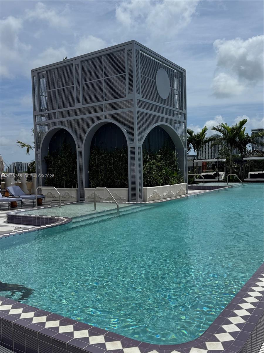 A swimming pool features a large, gray, perforated metal structure with arched openings and greenery — 2700 NW 2nd Ave # 240, Miami FL 33127, MIAMI, FL
