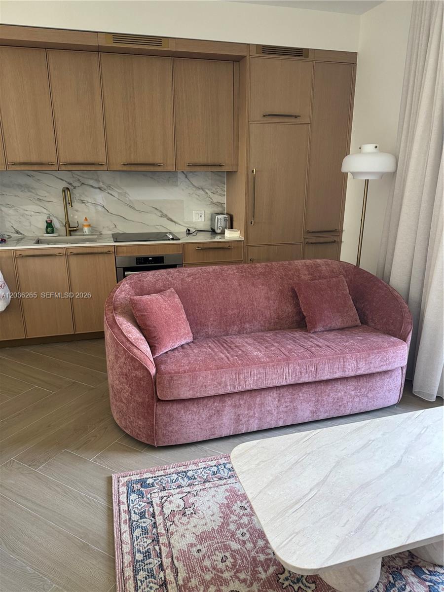 A pink velvet sofa sits in front of a kitchen with wood cabinets and marble backsplash — 2700 NW 2nd Ave # 240, Miami FL 33127, MIAMI, FL
