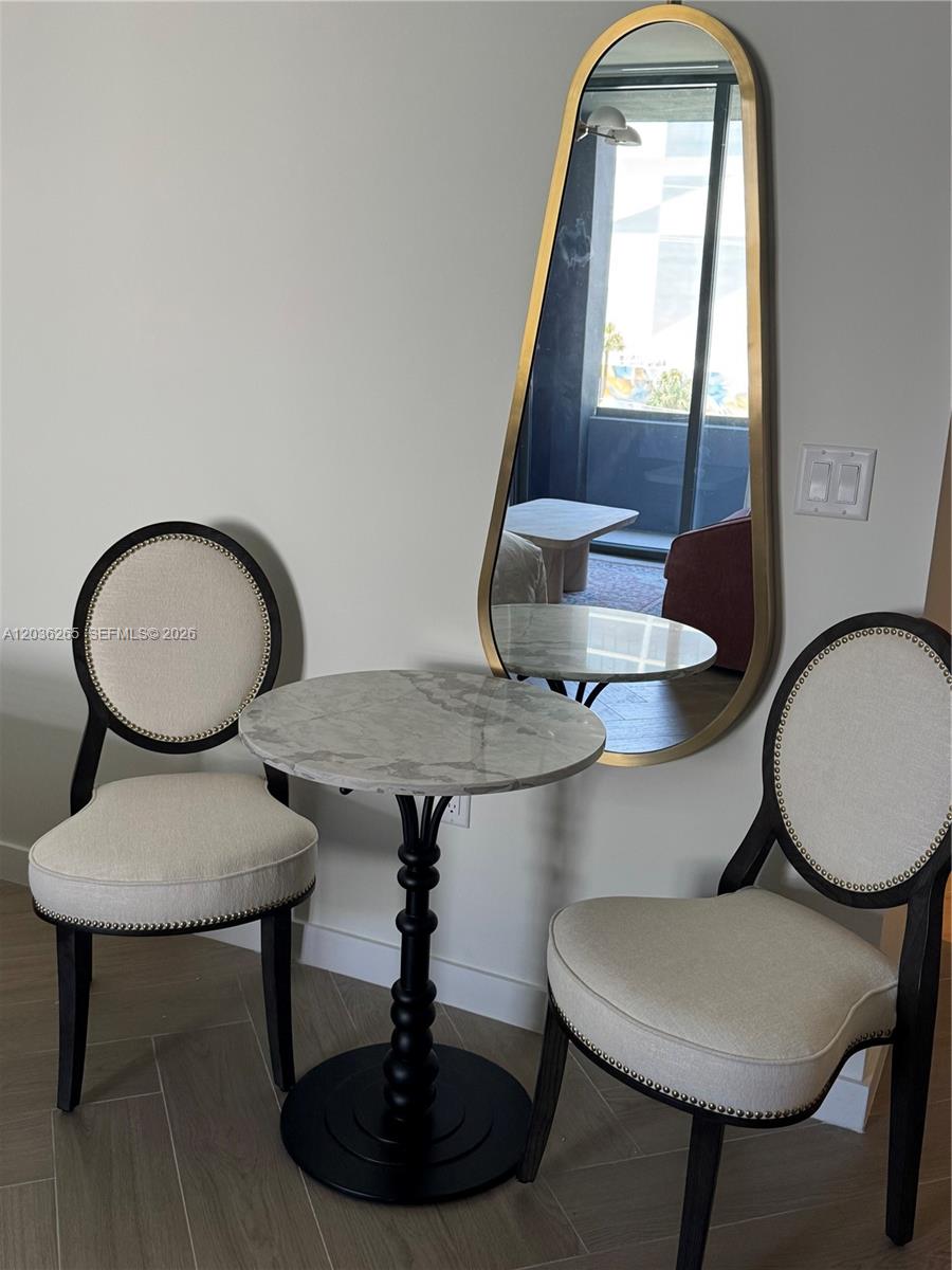 A small dining set with two upholstered chairs and a marble table sits before a mirror — 2700 NW 2nd Ave # 240, Miami FL 33127, MIAMI, FL