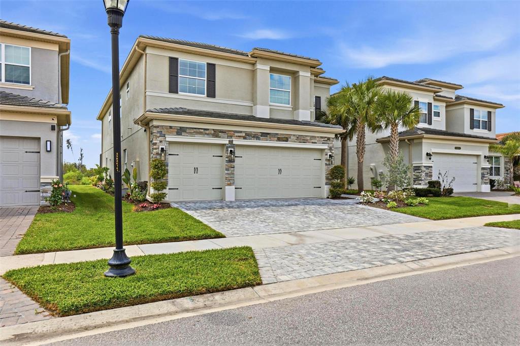 A two-story suburban house with a stone-accented facade and a paved driveway — 32490 TREE OF LIFE AVENUE, WESLEY CHAPEL, FL