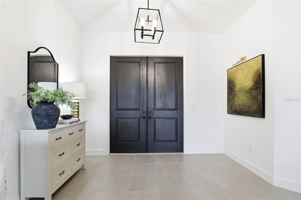 A bright entryway features a double black door, light tile floors, and a white dresser — 32490 TREE OF LIFE AVENUE, WESLEY CHAPEL, FL