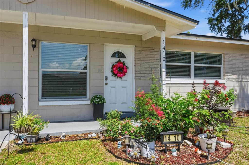 The exterior of a single-story house features a white front door and a landscaped garden — 1410 KOZART COURT, ORLANDO, FL