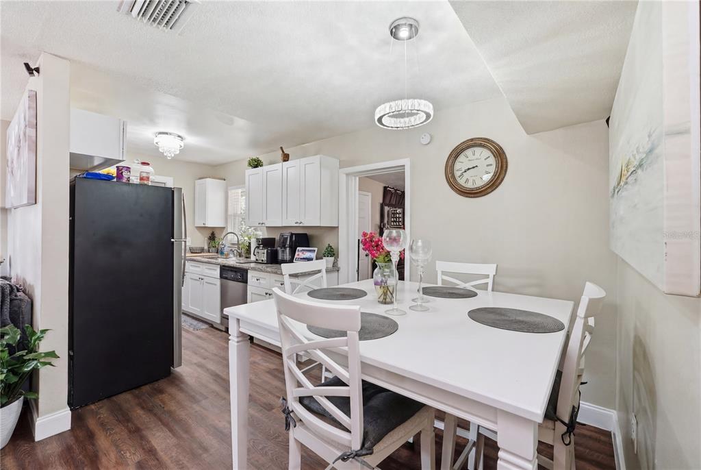 A dining area with a white table and chairs sits adjacent to a white kitchen — 1410 KOZART COURT, ORLANDO, FL
