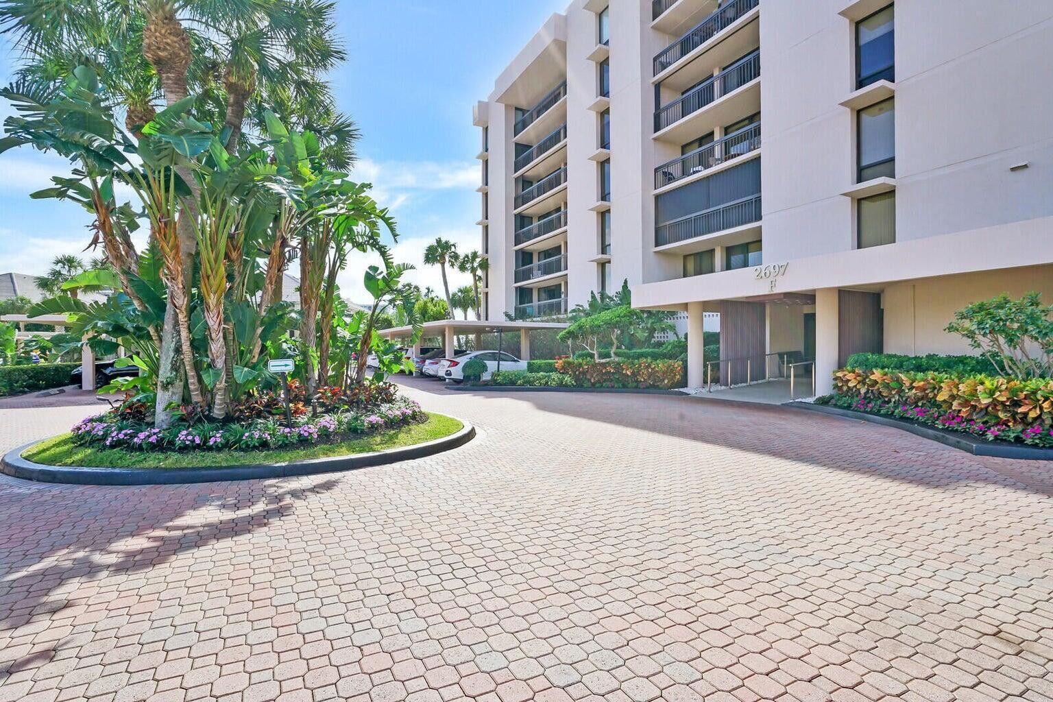 A paved driveway leads to the entrance of a multi-story apartment building with landscaping — 2697 N Ocean Boulevard # 604, Boca Raton FL 33431, BOCA RATON, FL