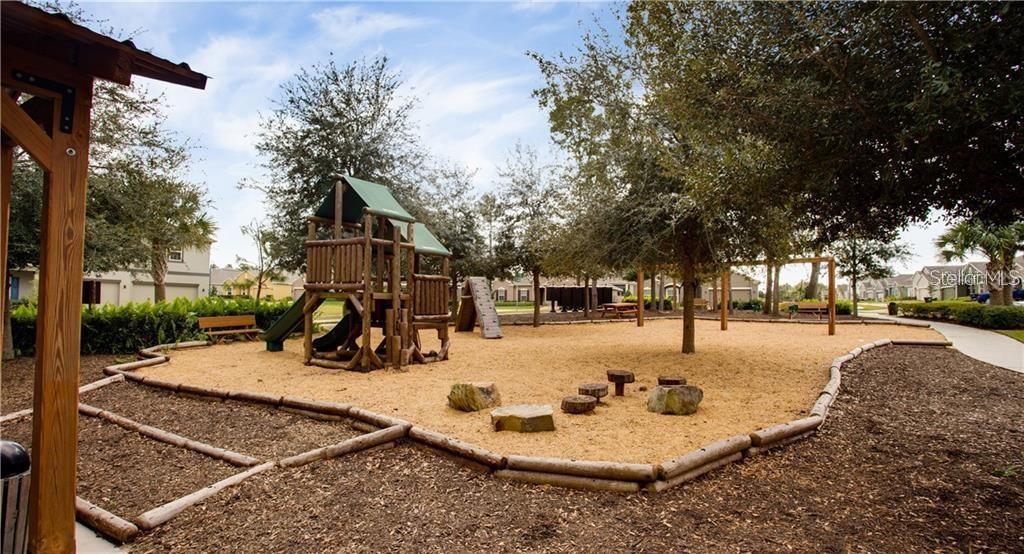 A playground with a wooden play structure, sand ground cover, and trees in a neighborhood — 2926 BLACK BIRCH DRIVE, OCOEE, FL