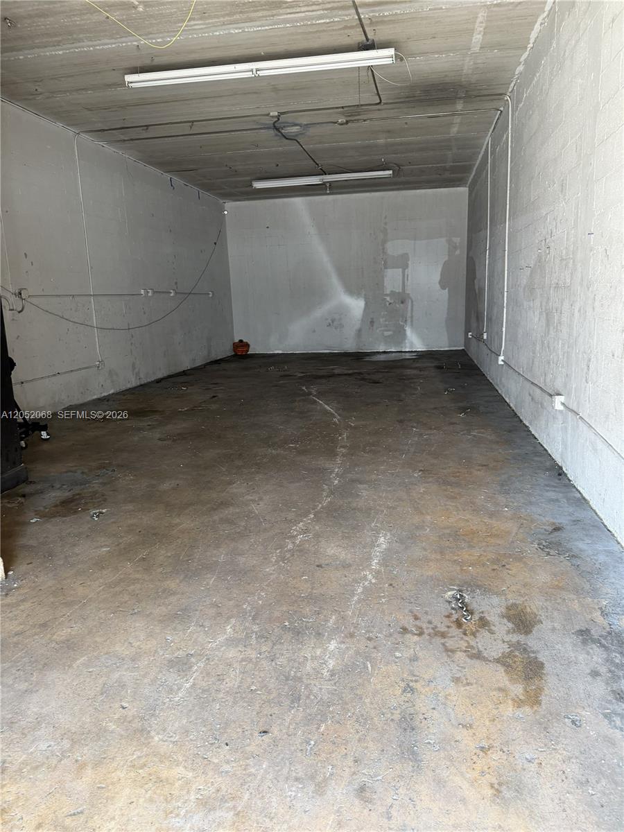 An empty, unfinished rectangular storage unit features concrete walls, a concrete floor, and overhead lighting — 2561 NW 23rd St, Miami FL 33142, MIAMI, FL