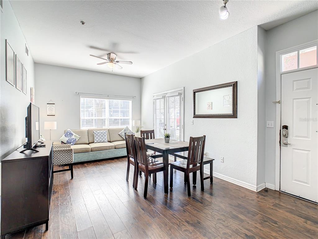 A living and dining area features dark wood flooring, a sofa, and a dining table — 2211 SAN VITTORINO CIRCLE UNIT 102, KISSIMMEE, FL