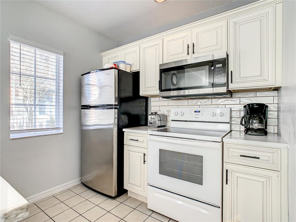 A kitchen features white cabinets, a stainless steel refrigerator, and a white electric range — 2211 SAN VITTORINO CIRCLE UNIT 102, KISSIMMEE, FL