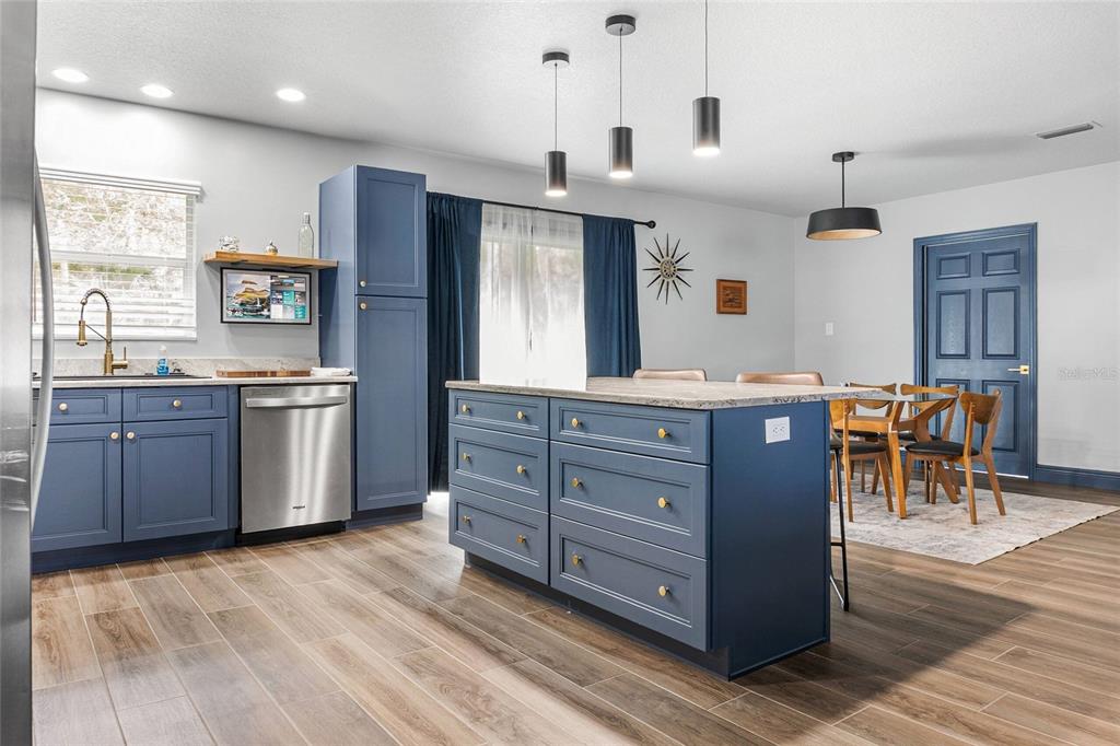 A kitchen with blue cabinets, a central island, and a dining area in the background — 3761 N HIAWATHA TER, CRYSTAL RIVER, FL