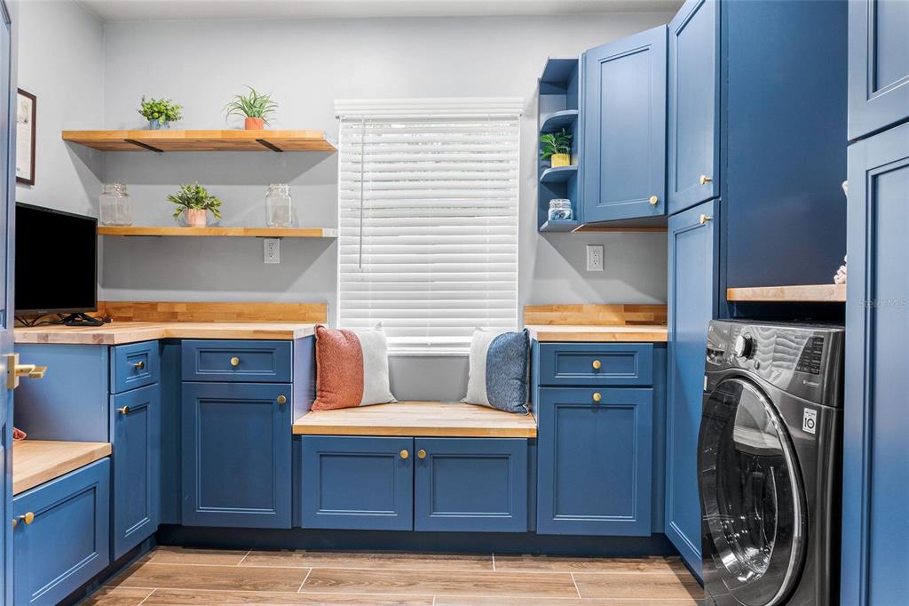 A laundry room features blue cabinets, wood countertops, open shelving, and a built-in window seat — 3761 N HIAWATHA TER, CRYSTAL RIVER, FL