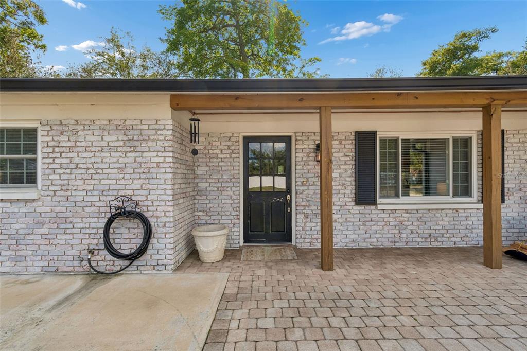 A white brick house exterior features a black front door, wooden porch posts, and pavers — 118 HORST ROAD, BRANDON, FL