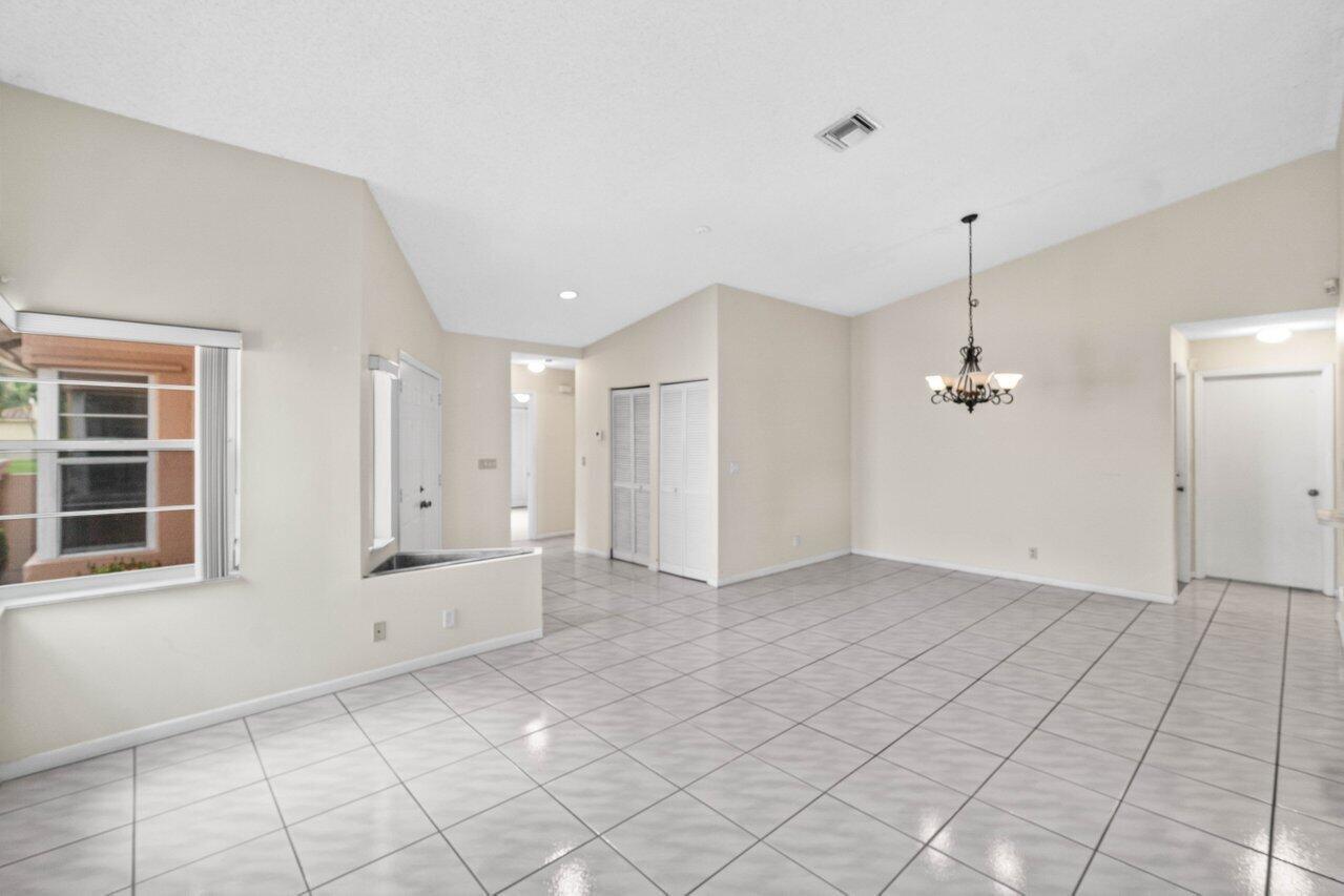 A bright, tiled dining area features a vaulted ceiling and a hanging chandelier — 10001 Country Brook Road, Boca Raton FL 33428, BOCA RATON, FL
