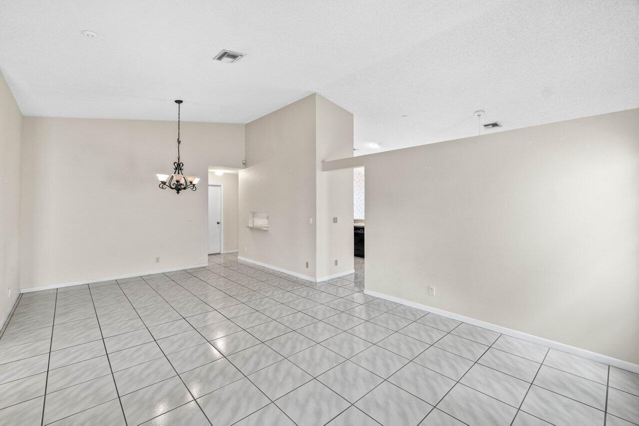 An open-concept dining area features light-colored tile flooring, beige walls, and a vaulted ceiling — 10001 Country Brook Road, Boca Raton FL 33428, BOCA RATON, FL