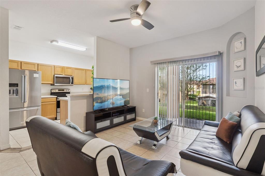 A living room with tile floors, a ceiling fan, and a sliding door to the patio — 245 CAMBRIA AVENUE, DAVENPORT, FL