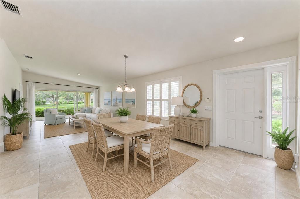 A dining area with a wooden table and wicker chairs next to a living room — 13275 HUERTA STREET, VENICE, FL