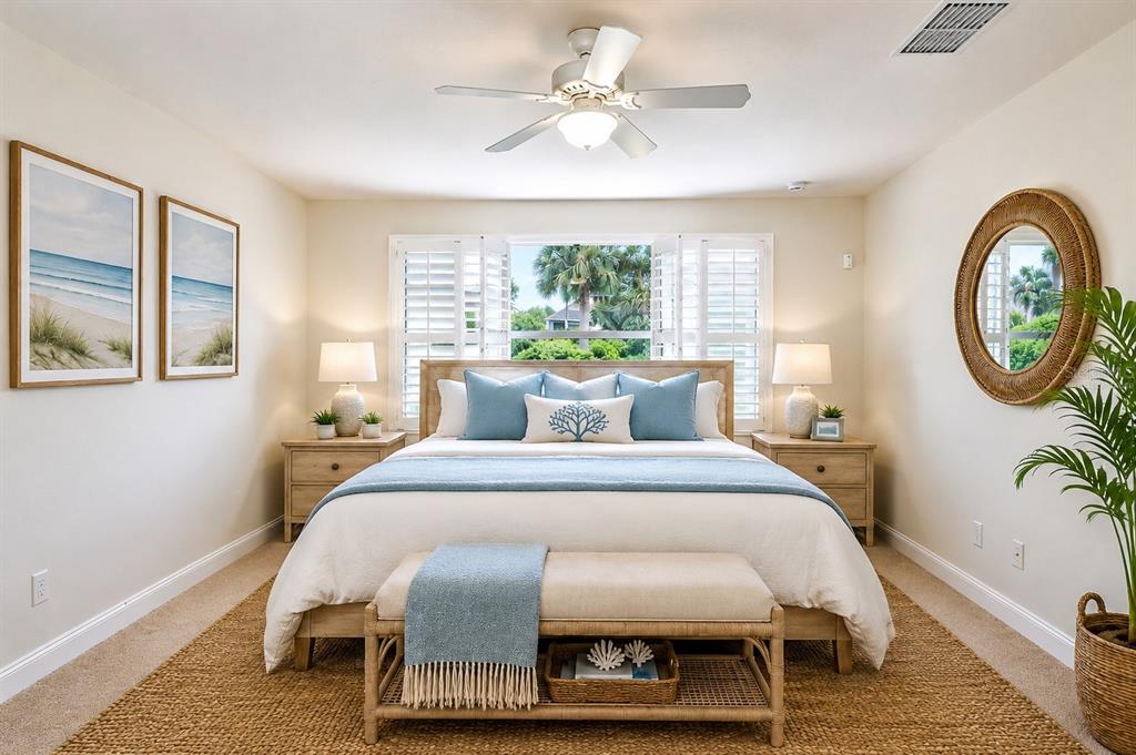 A coastal-style bedroom features a king bed, bedside tables, a ceiling fan, and window shutters — 13275 HUERTA STREET, VENICE, FL