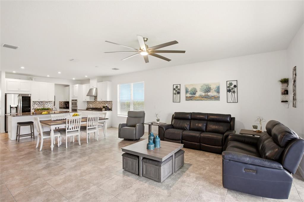 An open-concept living and dining area features tile flooring, white cabinetry, and leather furniture — 5720 MAIDENSTONE WAY, PALMETTO, FL