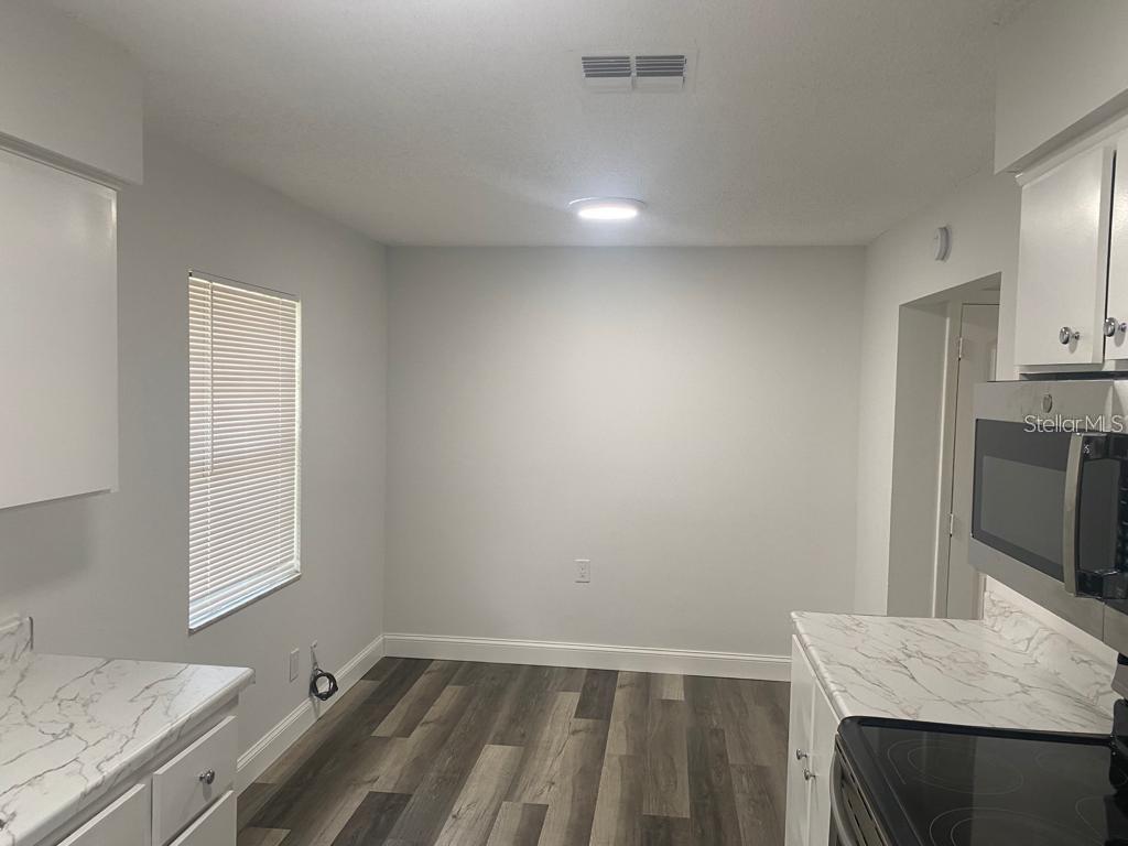 A kitchen with white cabinets, marble-look countertops, and wood-style flooring — 1815 WARFIELD PLACE, SEBRING, FL